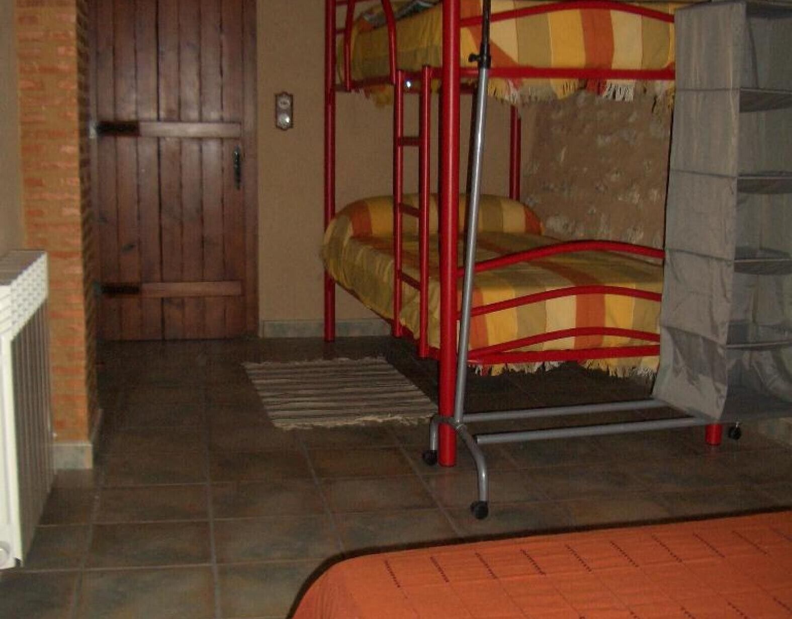 Ein Etagenbett mit rotem Gestell, einer Holztür und einem gefliesten Boden.