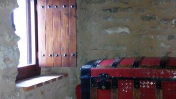 A room with a wooden wardrobe, a small window, and a red suitcase.
