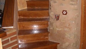 Uma escadaria de madeira com parede de pedra, base de tijolos e uma pequena placa.