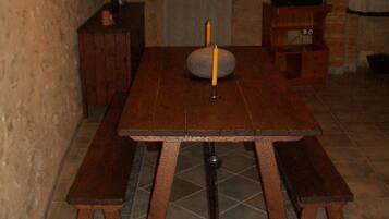 Una mesa de madera con bancos, un televisor sobre un mueble bajo y una vela sobre la mesa.
