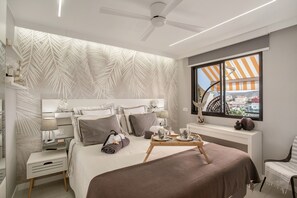 A modern hotel room with a bed, bedside table, lamp, and a view of the city through a window. - Vacation Apartment 'Estrella Del Mar Vista Al Puerto' with Sea View, Wi-Fi and Air Conditioning (Argueninguin)