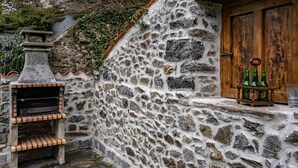 Un muro de piedra con una puerta de madera rústica y un pequeño estante con botellas.