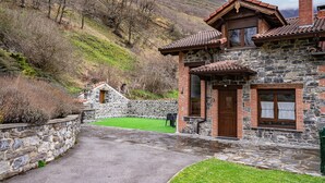Un edificio de piedra con un muro de piedra y un camino pavimentado que conduce a un césped verde.
