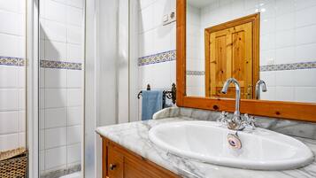 A bathroom with a marble sink, wooden vanity, and a mirror reflecting a wooden door.