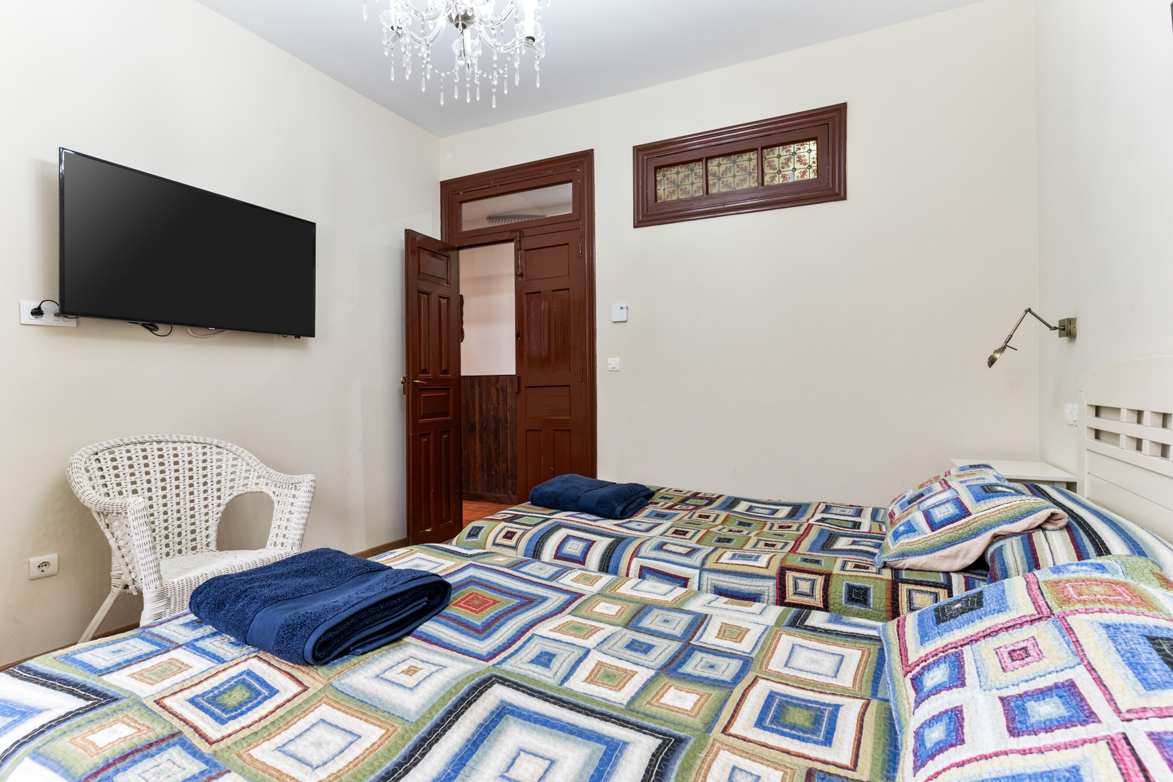 Une chambre à coucher avec un lit, une télévision, une chaise blanche et une porte.