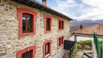 Un edificio de piedra con marcos de ventana rojos y techo de tejas.