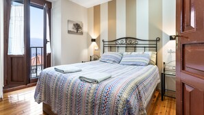 Een slaapkamer met een bed, een raam, een deur en een wandlamp.