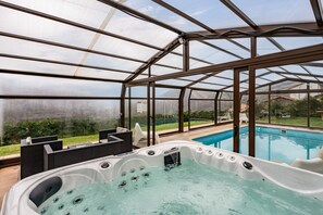 A hot tub inside a greenhouse with a pool outside. - Rural House 'La Cerra' with Mountain Views, Private Pool, and Wi-Fi (Lena)
