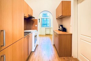 Cocina estrecha con armarios de madera, estufa y ventana con vistas.