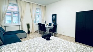 A bedroom with a bed, a sofa, a dining table with chairs, a potted plant, and a wardrobe. - Affordable 2BR Apartment; Close to Danube River (Vienna)