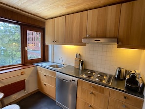 Una cocina moderna con armarios de madera, lavavajillas de acero inoxidable y cocina a gas.