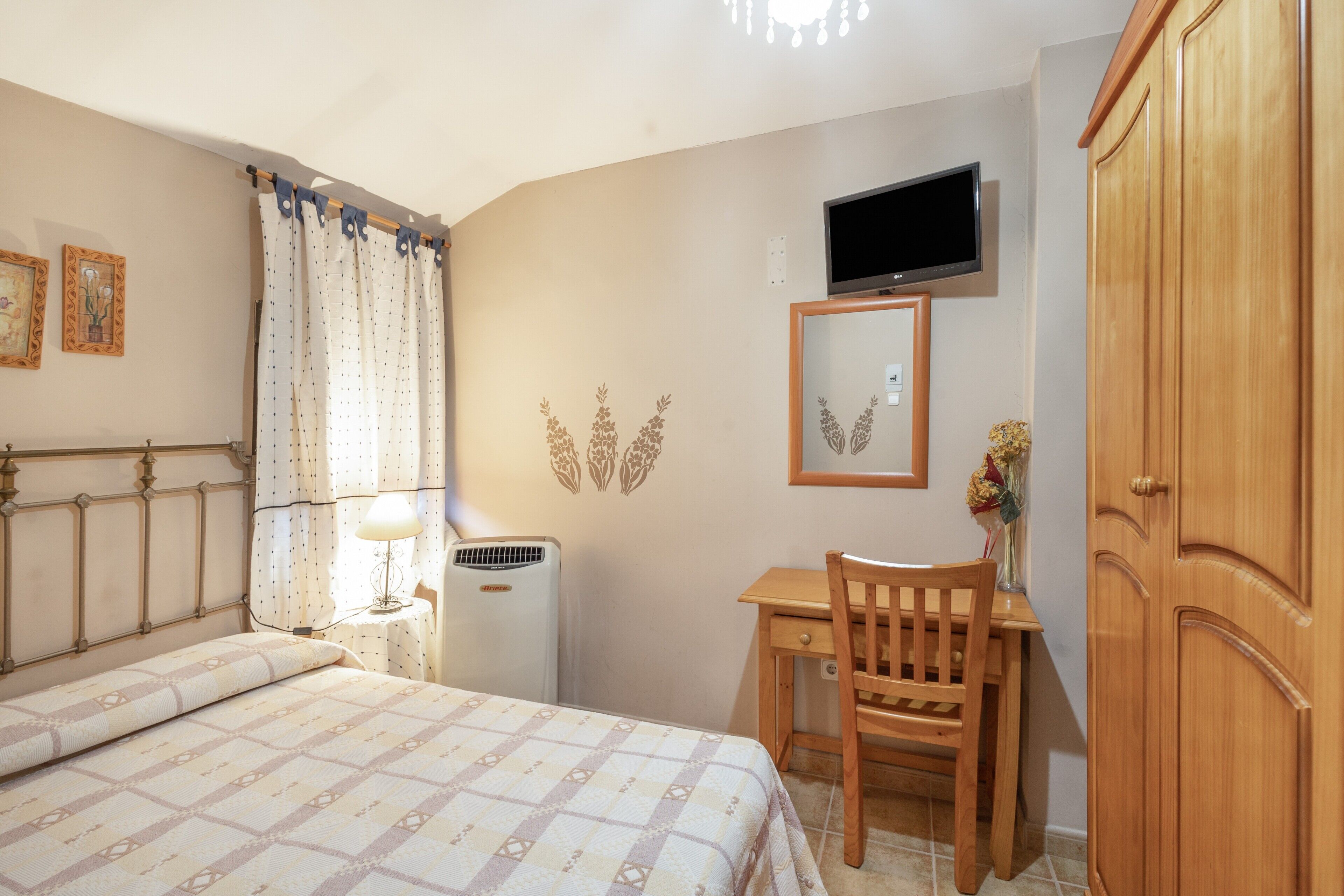 Une chambre à coucher comprenant un lit, un bureau, une chaise, une télévision et une armoire.