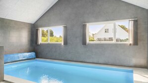 Una piscina interior con techo inclinado y paredes grises.
