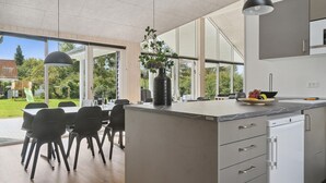 Una cocina moderna con una isla grande, un comedor con sillas y vistas al exterior.