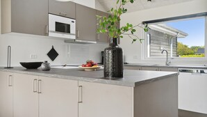Una cocina moderna con una isla central, un microondas y un florero con plantas verdes.