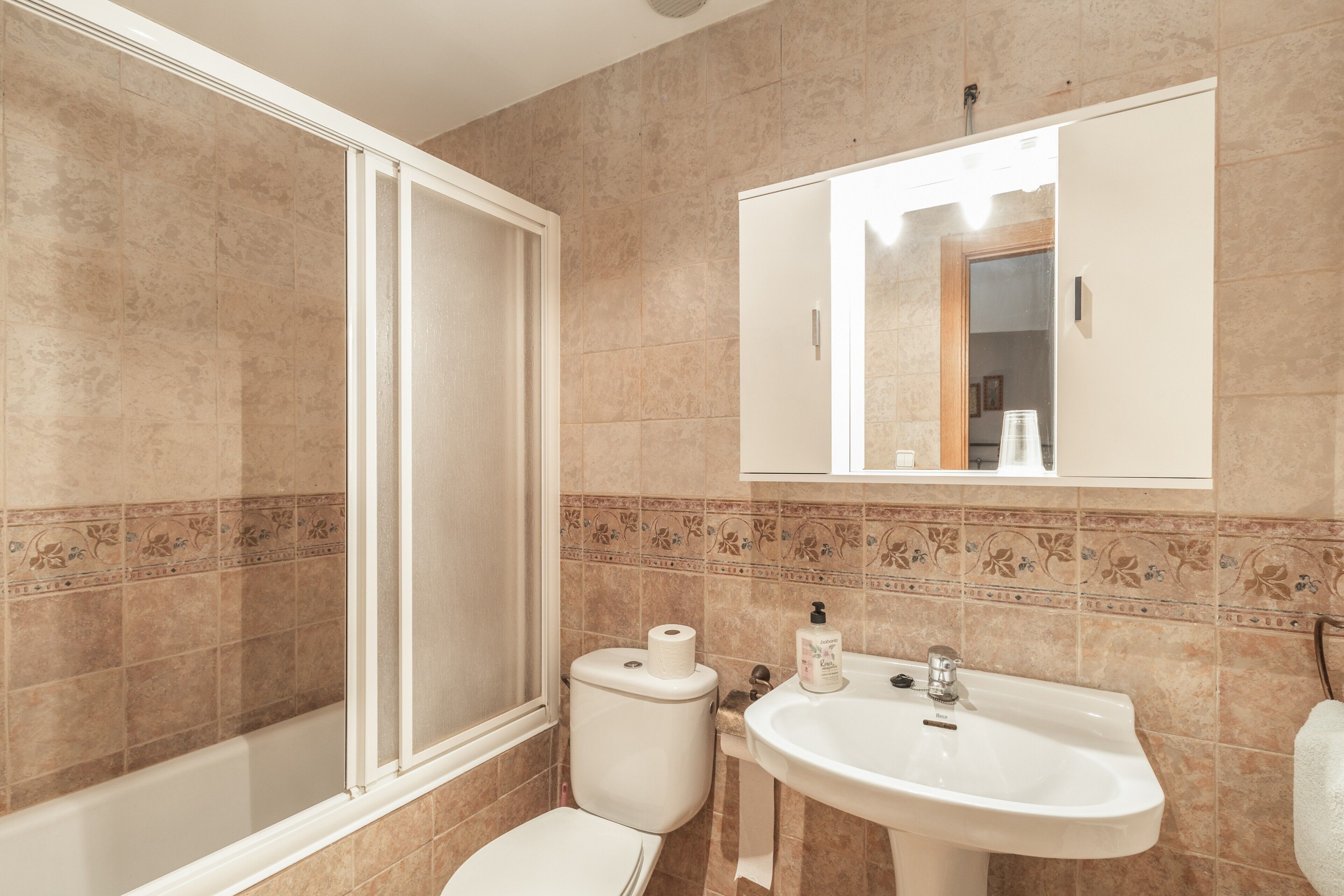 Une salle de bain équipée d’une douche, de toilettes, d’un lavabo et d’un miroir.