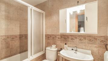Une salle de bain équipée d’une douche, de toilettes, d’un lavabo et d’un miroir.