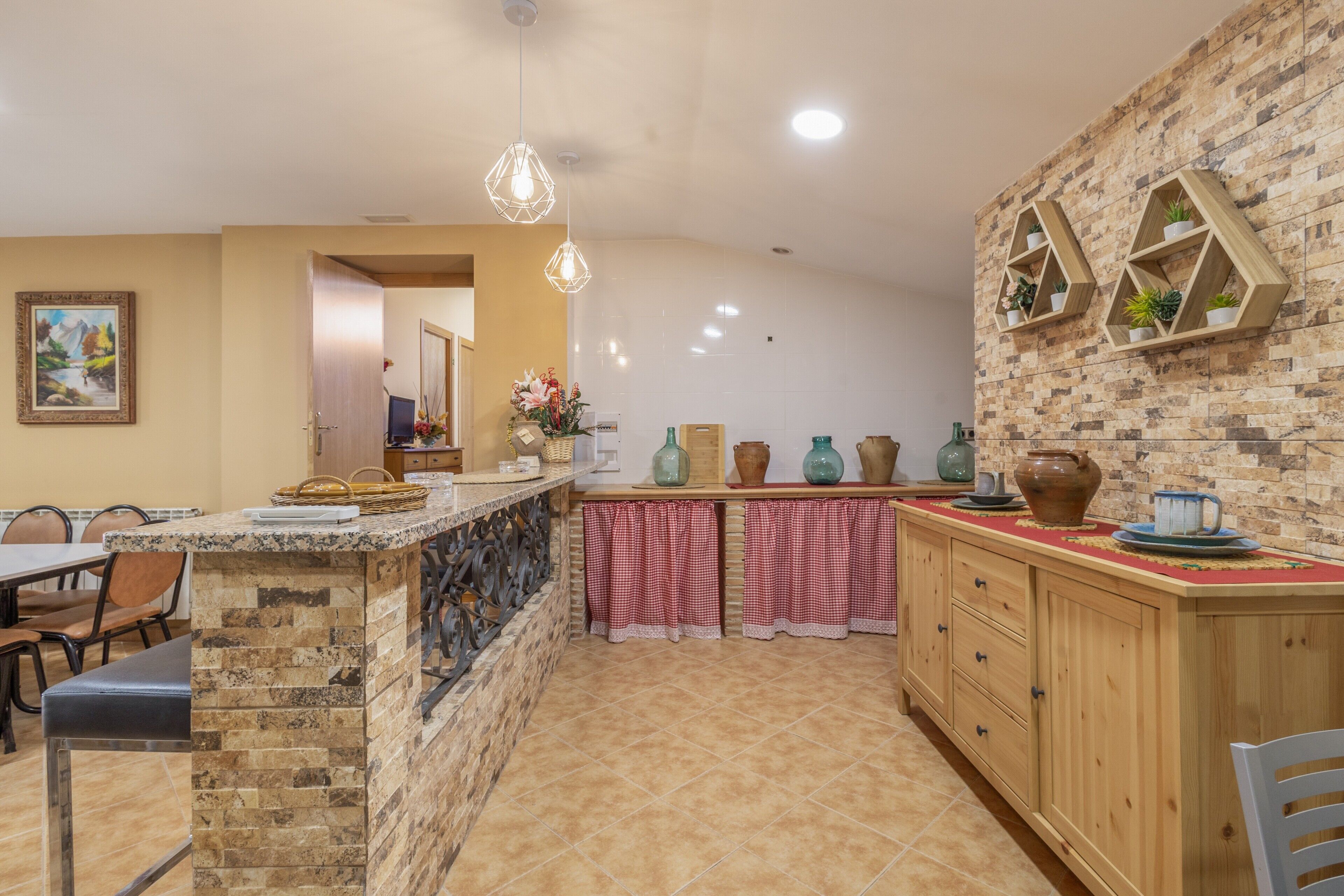 Una cocina con una isla de piedra, armarios de madera y estantes decorativos en la pared.