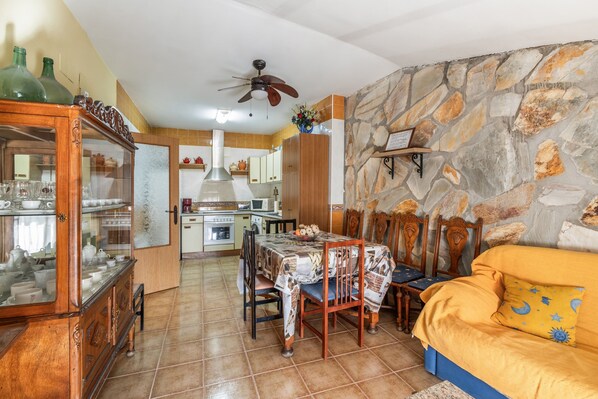 A dining area with a table set for four, a sofa, and a stone wall.