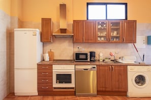 Una cocina compacta equipada con refrigerador, horno, lavavajillas, microondas y lavadora.