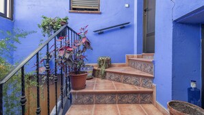 Un edificio azul con escaleras, plantas en macetas y barandilla de metal.