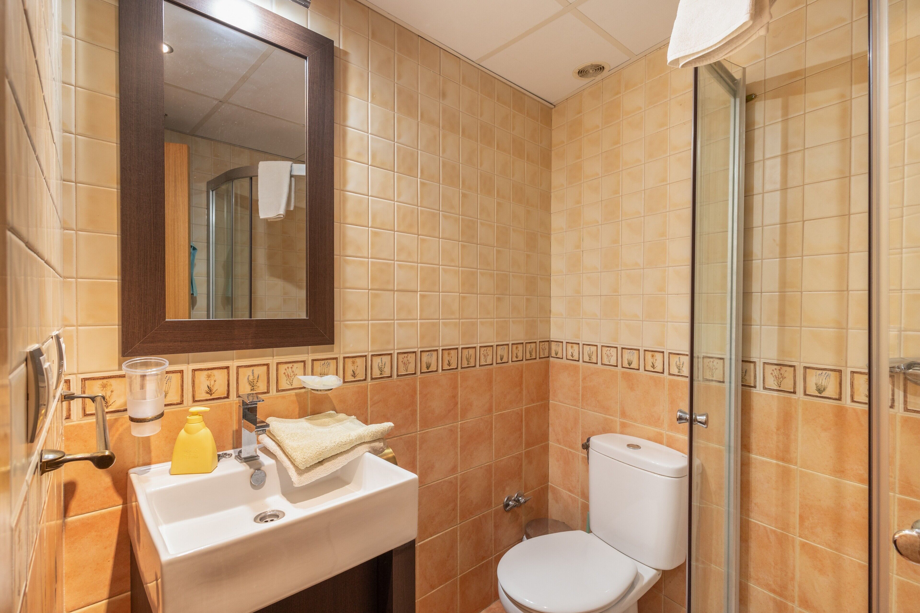 A bathroom with a sink, mirror, toilet, and shower.