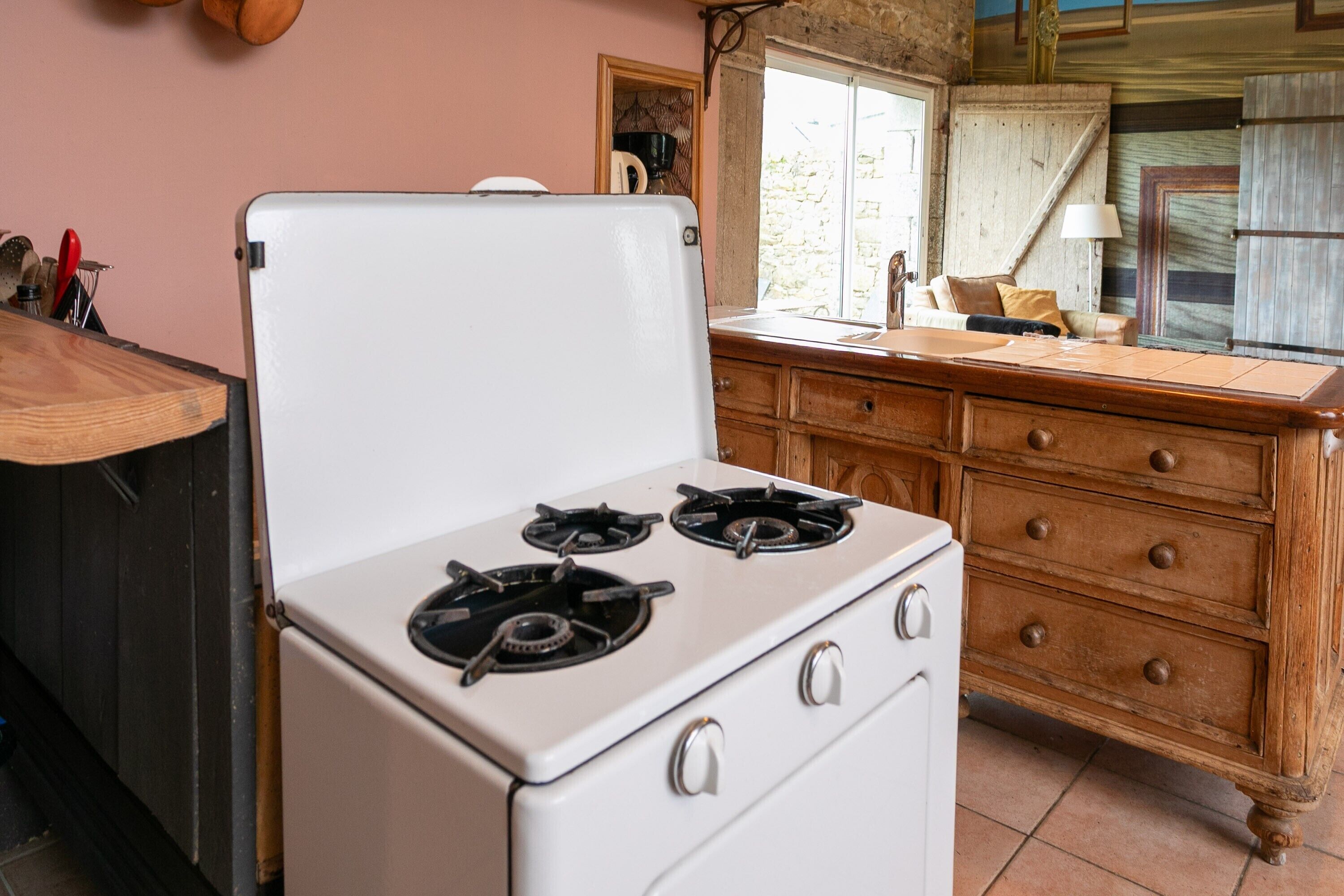 A kitchen with a white stove, wooden cabinets, and a window.