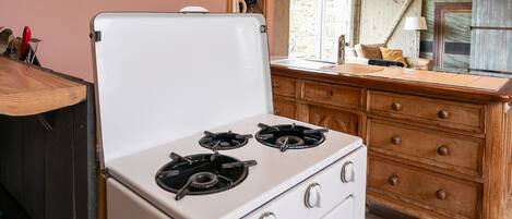 A kitchen with a white stove, wooden cabinets, and a window.