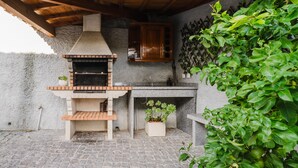 Una barbacoa de piedra con chimenea, un lavadero y un armario de madera.