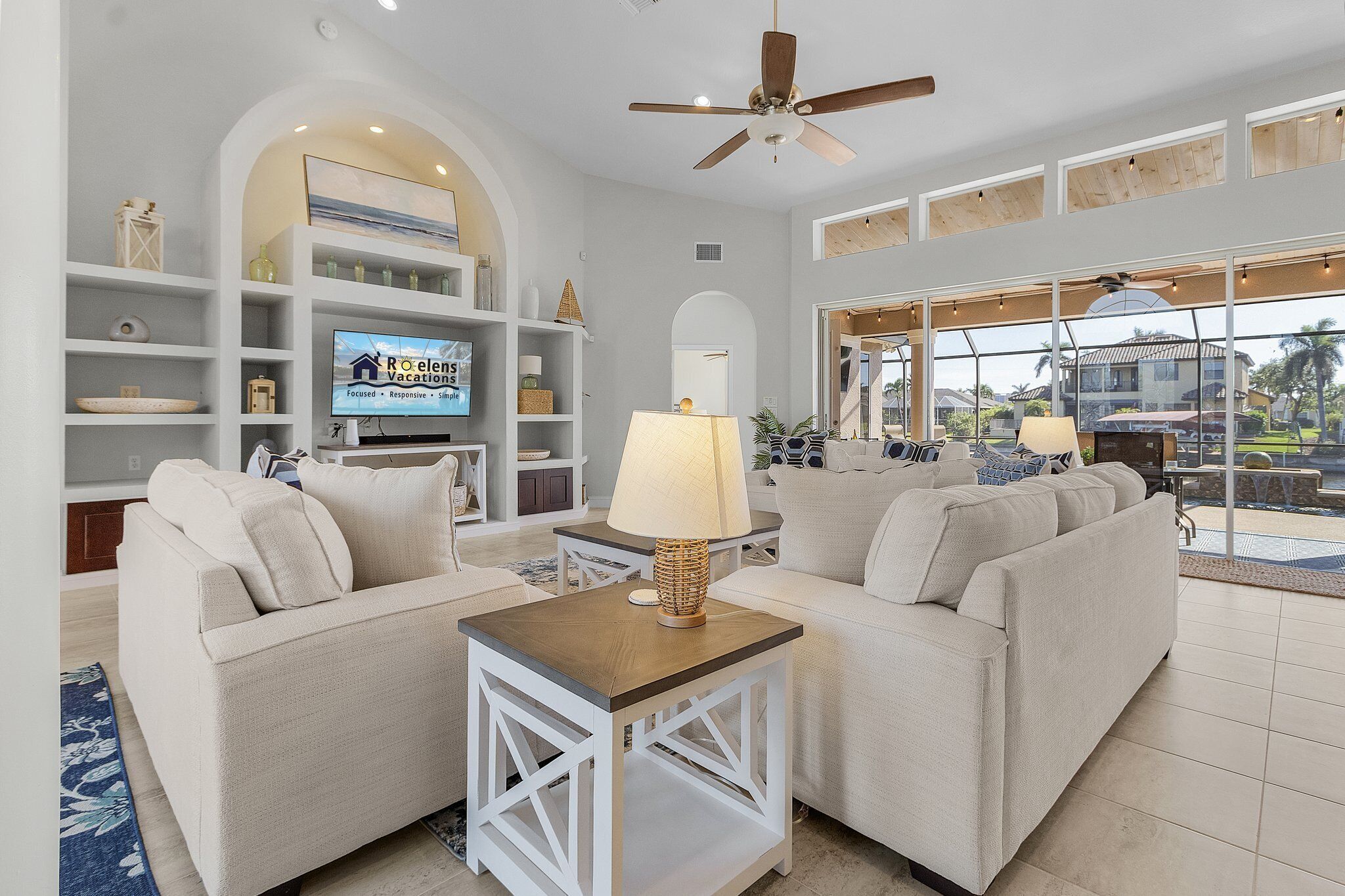 A modern living room with a sofa set, a TV, and a ceiling fan.