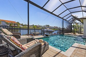 A covered outdoor swimming pool with lounge chairs and a view of a residential area. - Stunning! Gulf Access, Heated Pool -Harbor Lights Hideaway - Roelens (Cape Coral)