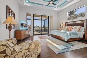 A bedroom with a bed, a dresser, a sofa, and a large window with a view. - Stunning! Gulf Access, Heated Pool -Harbor Lights Hideaway - Roelens (Cape Coral)