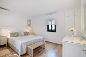 A modern bedroom with a bed, bedside tables, a window, and a small desk with a vase. - Pear Tree Holiday Home with Private Terrace, Wi-Fi, and Air Conditioning (Vale de Lobo)