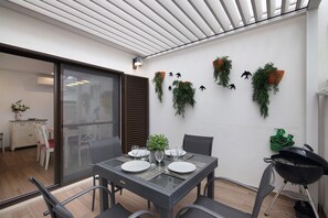 Een moderne eetruimte met een glazen tafel, stoelen en een grill.