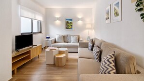 Uma sala de estar moderna com televisão de tela plana, sofá, mesa de centro e mesa lateral.