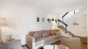 Uma sala de estar moderna com um sofá, uma mesa de centro, um abajur e uma escada.