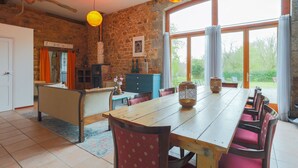 A dining area with a wooden table, chairs, and a view of the outdoors. - Holiday Home 'Gite La Grange 6 Personnes' with Shared Pool, Private Terrace and Wi-Fi (Prat)