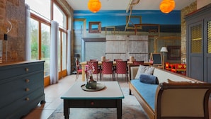 A room with a dining area, a sofa, and a table with a vase. - Holiday Home 'Gite La Grange 6 Personnes' with Shared Pool, Private Terrace and Wi-Fi (Prat)