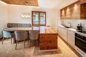 Une cuisine moderne avec des meubles en bois, une table à manger avec des chaises et un four encastré.