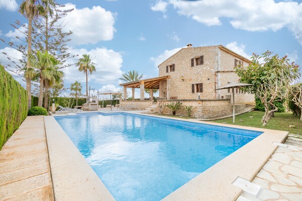 A stone house with a swimming pool, a covered patio, and a well-maintained garden. - Country House 'Can Segarut' with Private Pool, Private Terrace and Wi-Fi (Illes Balears)