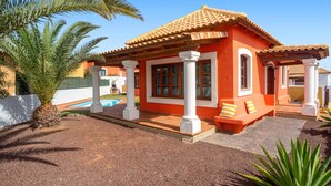 Une maison avec un toit en tuiles, des colonnes blanches et une piscine.