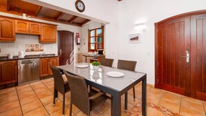 Une cuisine moderne avec des meubles en bois, une table à manger avec des chaises et une grande porte en bois.