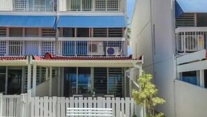 A multi-story building with balconies, a white fence, and a bench in the courtyard. - Ocean view villa walking distance to restaurants, public beach and more (Dorado)