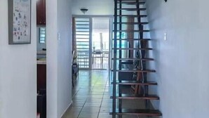 A hallway with a tiled floor, a staircase, and a door leading to another room. - Ocean view villa walking distance to restaurants, public beach and more (Dorado)