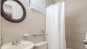 A bathroom with a sink, toilet, and shower curtain. - Ocean view villa walking distance to restaurants, public beach and more (Dorado)