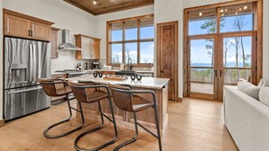 Una cocina moderna con armarios de madera, electrodomésticos de acero inoxidable y una isla grande con taburetes de bar.
