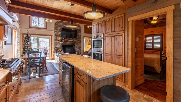 A spacious kitchen with wooden cabinets, a granite countertop, and a stone fireplace.