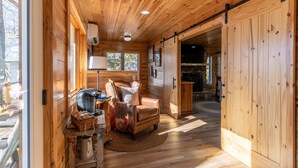 A wooden cabin interior with a cozy living area featuring a sofa, a coffee table, and a fireplace.