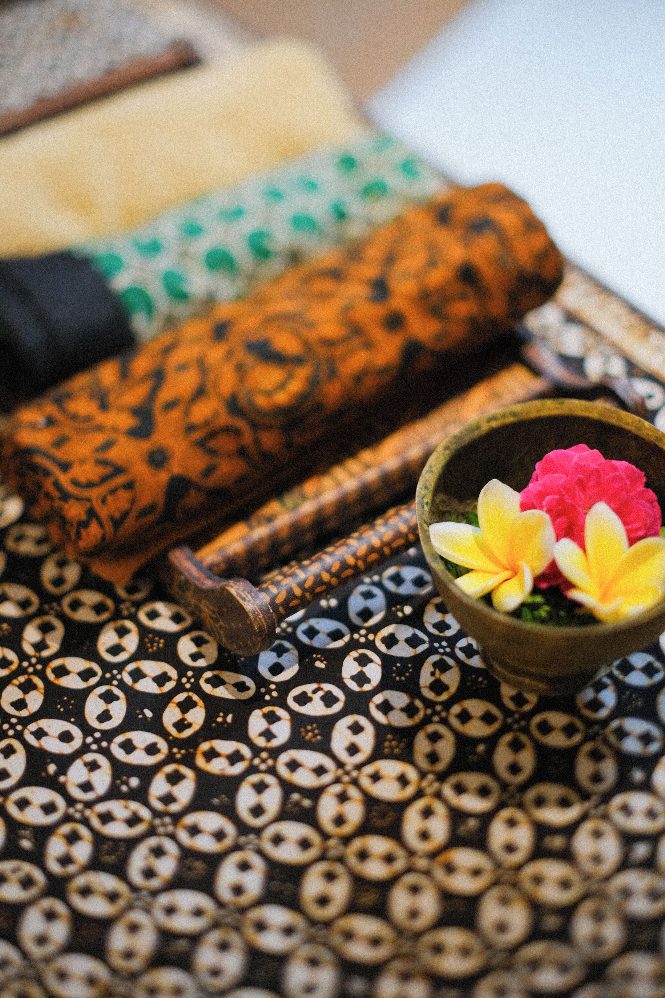 A patterned fabric with a bowl of flowers and a rolled-up item.