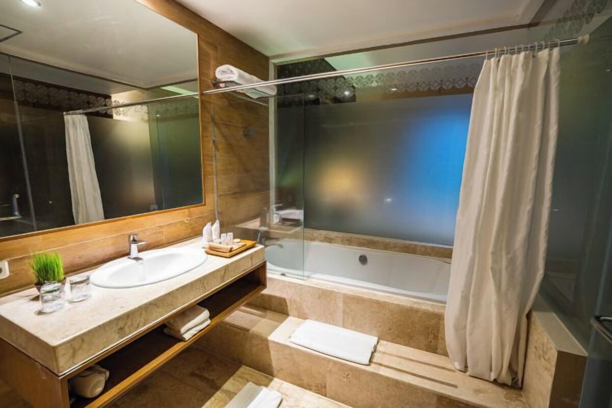 Un bagno moderno con doccia vetrata, uno specchio grande e un vanità in marmo.
